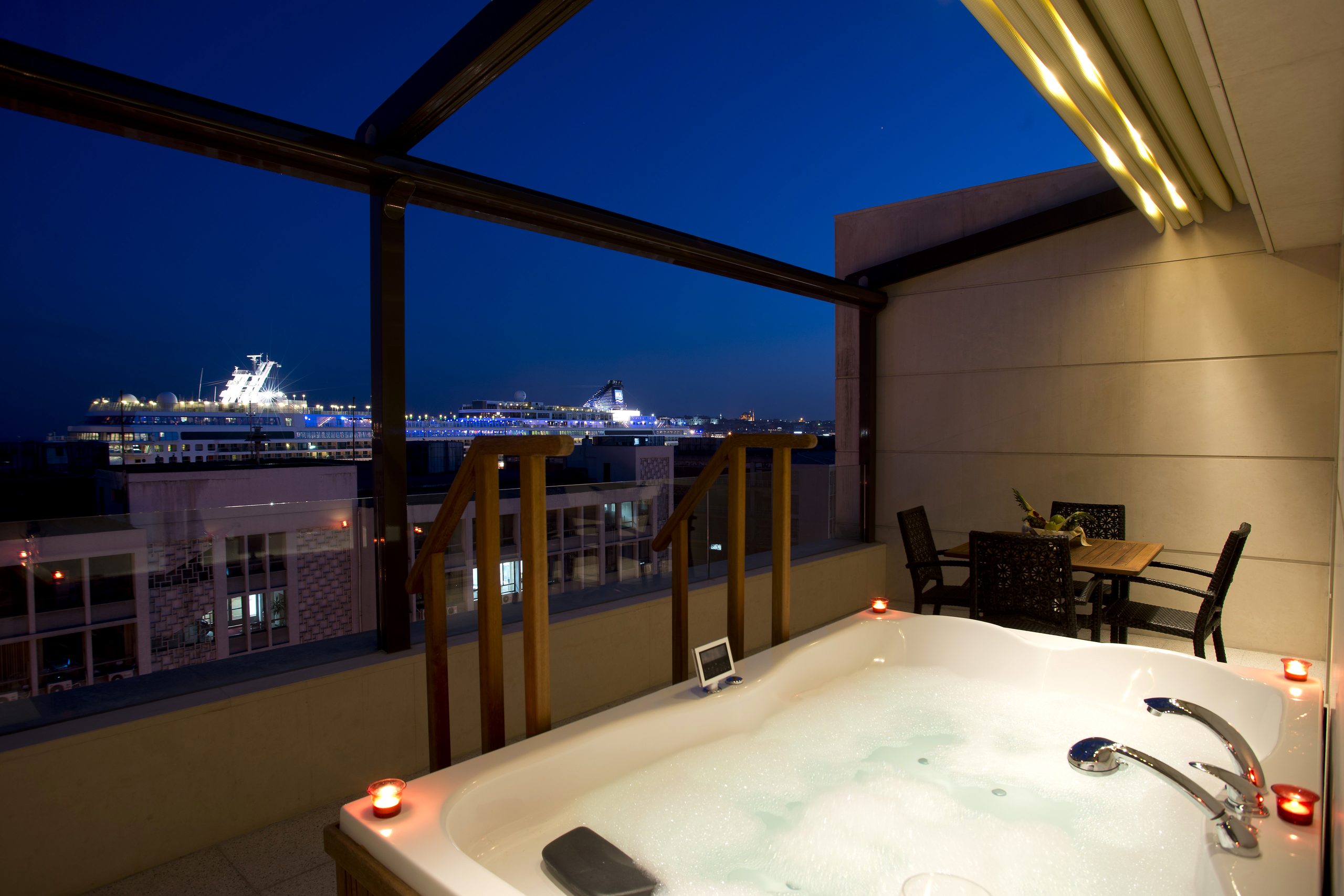 Jacuzzi on the Bosphorus Suite terrace at night, a cruise ship at Galataport behind