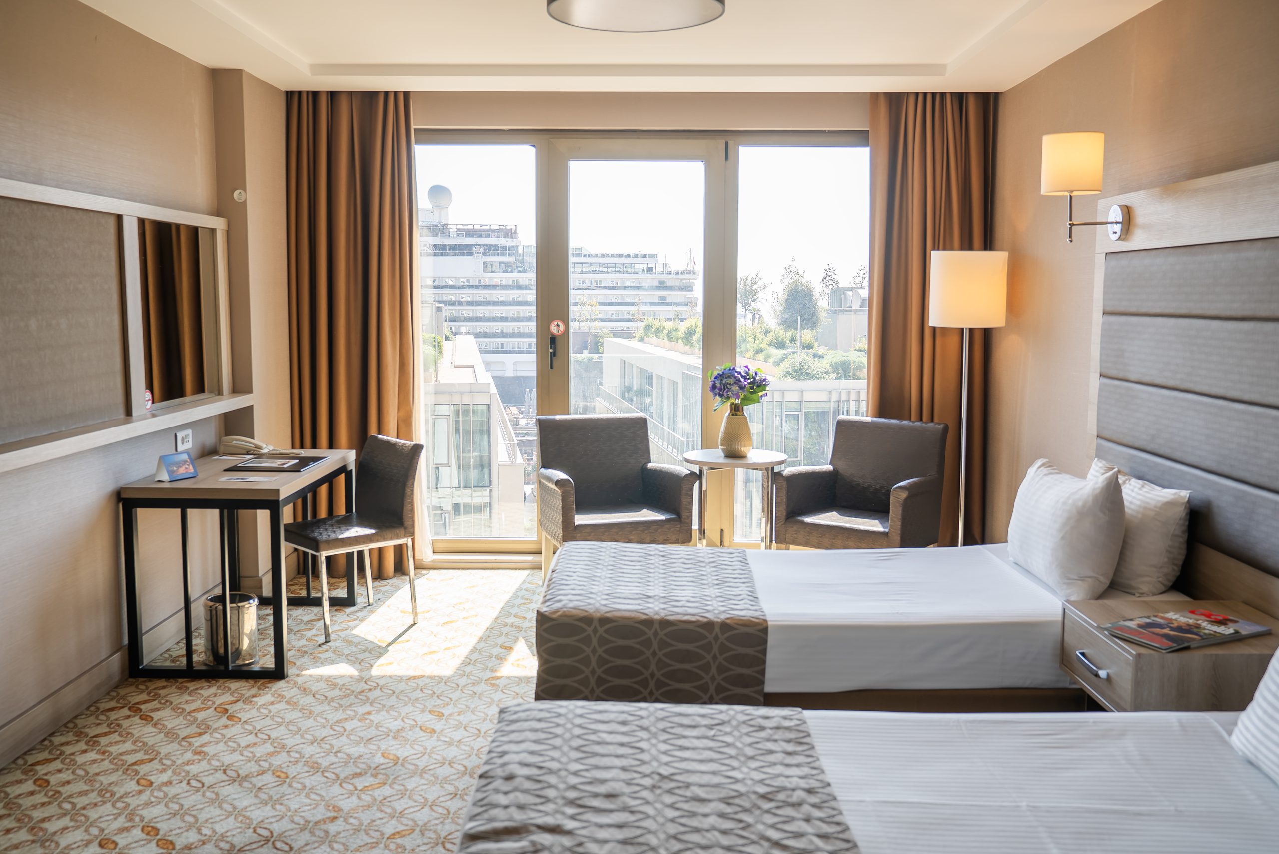 Superior triple room: armchairs by the window and a desk